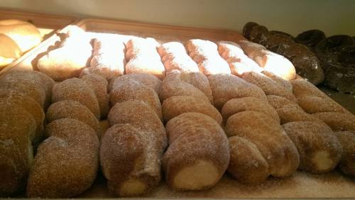 A tray of freshly baked, sugar-coated pastries arranged in rows, with soft lighting highlighting their texture.