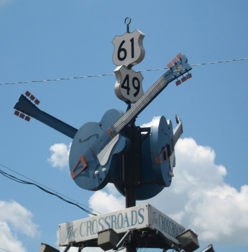 Signpost featuring guitars and highway numbers 61 and 49 against a blue sky.