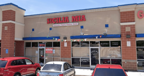 Exterior of Sicilia Mia restaurant with a red car parked outside, featuring an "Open" sign and festive decorations.