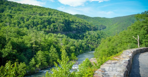 A scenic view of a river winding through lush green mountains under a clear blue sky.