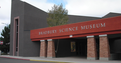 Exterior of the Bradbury Science Museum, featuring a modern design with a red and gray facade and a tree nearby.
