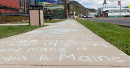 Sidewalk with chalk writing about the Appalachian Trail, noting its length and states it passes through.