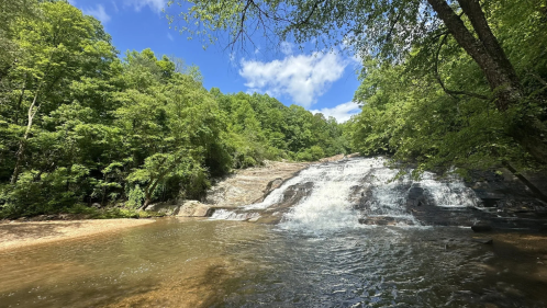 A wide river flows down rocky cliffs on a sunny day near Elkin, NC.