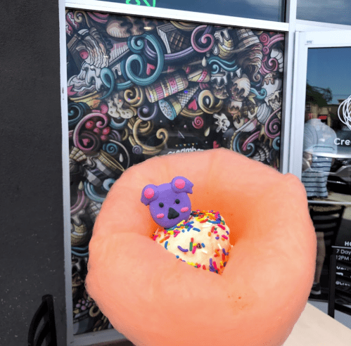 A large cotton candy bowl holds ice cream topped with colorful sprinkles and a cute purple bear cookie.