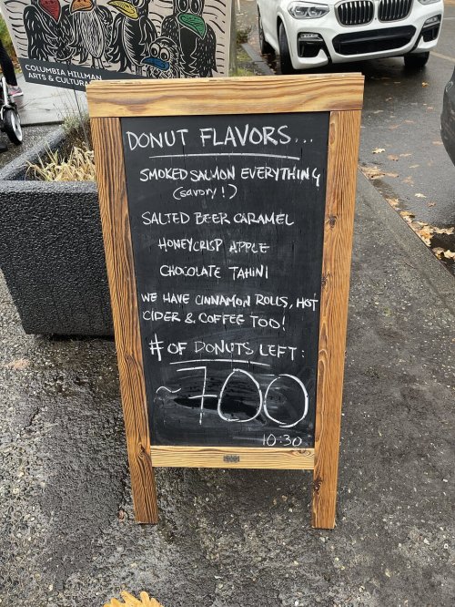 A chalkboard sign listing donut flavors: smoked salmon, salted beer caramel, honeycrisp apple, chocolate tahini, and more.