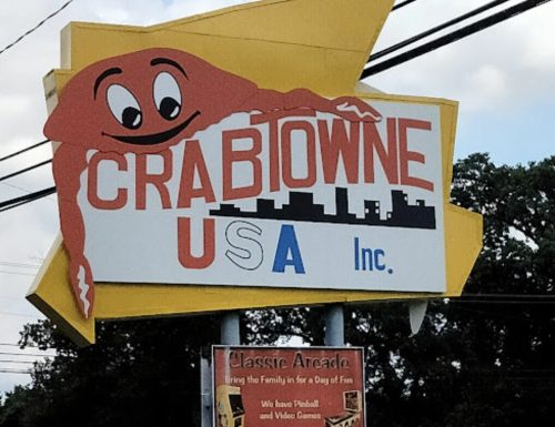 Sign for Crabowne USA Inc. featuring a cartoon crab and promoting a classic arcade with games and family fun.
