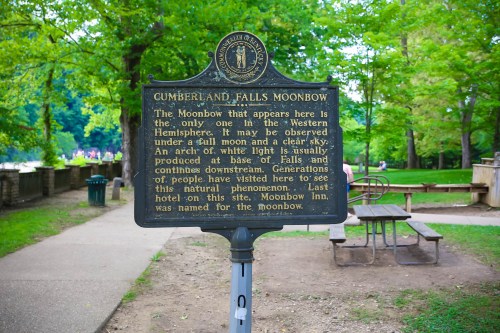 Sign about the Cumberland Falls Moonbow, explaining its occurrence under a full moon and clear sky, surrounded by greenery.