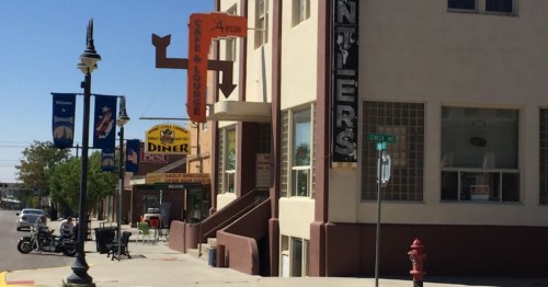 A street view featuring a café, diner, and lounge with colorful signs and parked motorcycles.