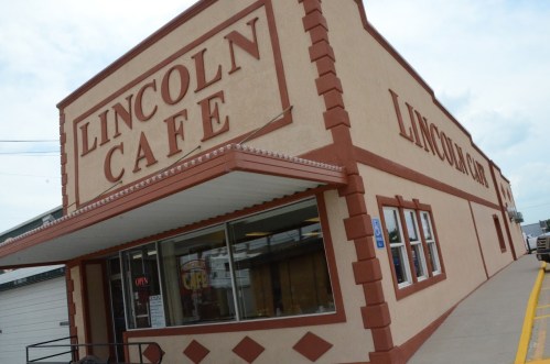 Exterior of Lincoln Cafe, featuring a large sign and a welcoming entrance, with a cloudy sky in the background.
