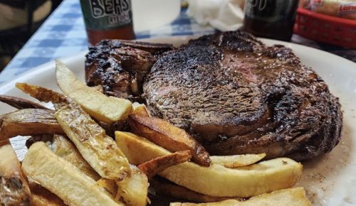 A plate featuring a large, grilled steak alongside golden, crispy French fries.