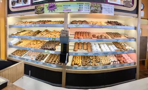 A display case filled with various types of donuts, including glazed, chocolate, and sprinkled varieties.