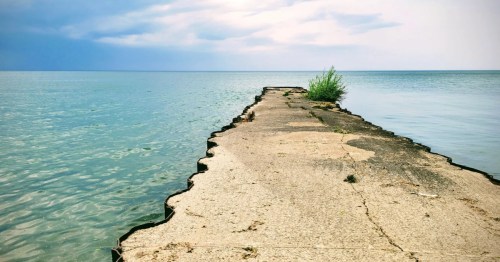 Concrete pier extending into the blue waters of Lake Ontario at Fair Haven Beach State Park in New York.