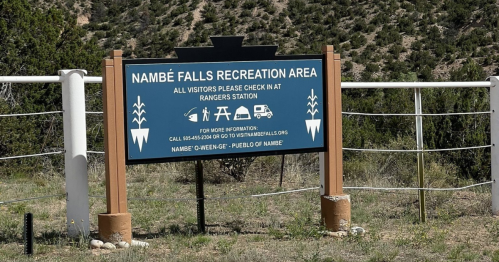 Sign for Nambé Falls Recreation Area, instructing visitors to check in at the ranger station for information.