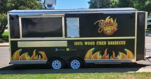 A food truck with a black exterior featuring flames and the text "York's Barbecue Pit - 100% Wood Fired Barbecue."
