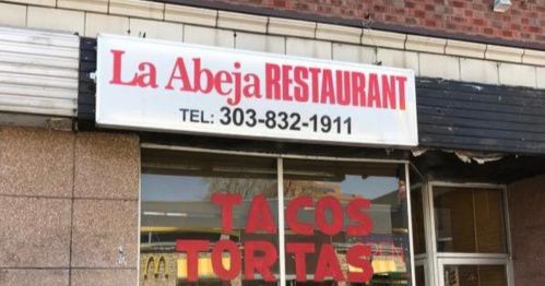 Sign for La Abeja Restaurant featuring "Tacos Tortas" and a contact number.