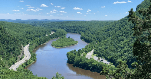 A scenic view of a winding river surrounded by lush green hills under a clear blue sky.
