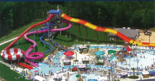 Aerial view of a water park featuring colorful slides, a large pool, and numerous visitors enjoying the attractions.