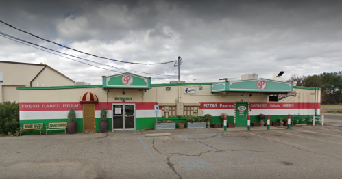 A colorful restaurant exterior with a sign for pizzas, pastas, and sandwiches, featuring a welcoming entrance.