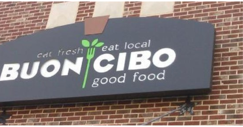 Sign for Buon Cibo, featuring the slogan "Eat fresh, eat local" and "Good food" on a brick wall background.