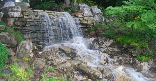 A serene waterfall cascading over rocks, surrounded by lush greenery and vibrant plants.
