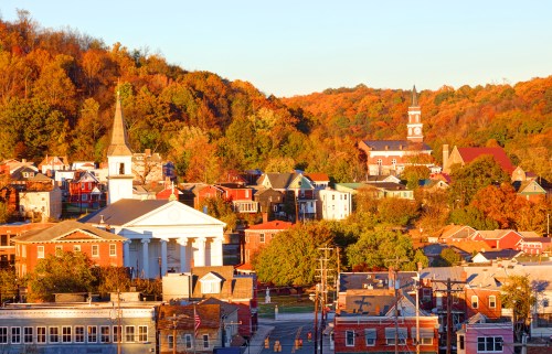 A scenic view of a small town with colorful autumn foliage, featuring a church steeple and historic buildings.