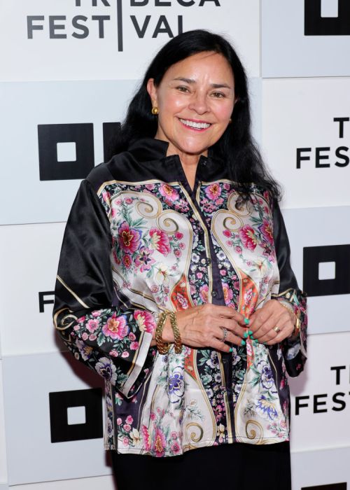 A woman in a floral-patterned blouse smiles at the Tribeca Festival event backdrop.