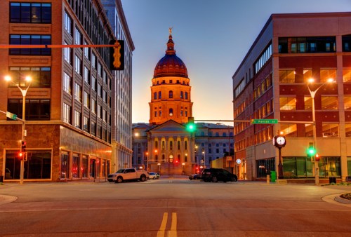 Sunrise over a city intersection, featuring a historic dome building and modern architecture on either side.