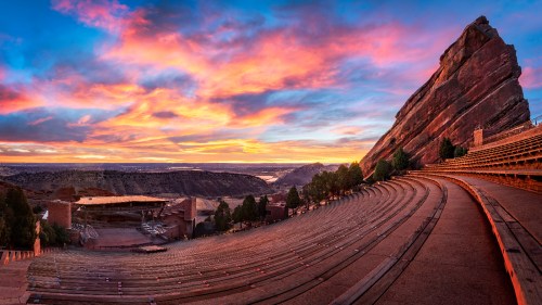 A panoramic view of Red Rocks Amphitheatre at sunset, showcasing vibrant skies and natural rock formations.