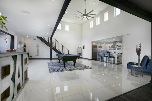 Modern interior featuring a pool table, sleek bar, and open space with large windows and stylish decor.