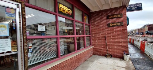 Exterior of a bakery with large windows, displaying signs for "Ziegler's" and "Kossers," in a brick building.