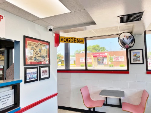 Interior of a fast-food restaurant featuring a wall with framed photos, a mirror, and a sign for Ogden Avenue.