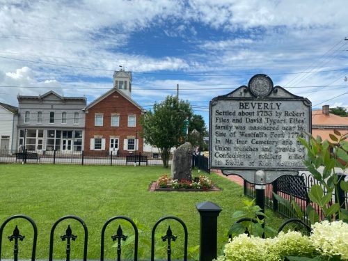 Historic marker in Beverly, WV, with a grassy area and buildings in the background under a blue sky.