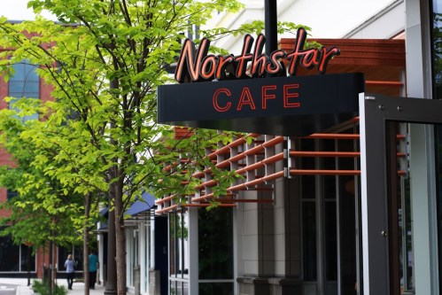 Sign for Northstar Cafe with greenery in front, showcasing a modern building entrance.