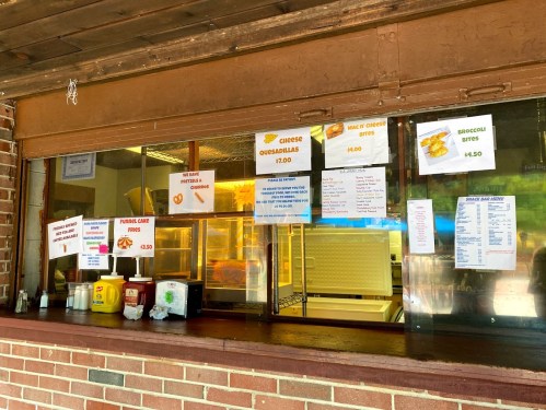 A food stand window displaying a menu with prices for various items like quesadillas and broccoli bites.