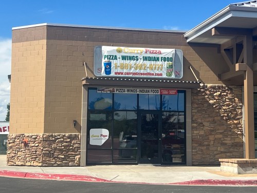 Exterior of a restaurant featuring a sign for "Curry Pizza" offering pizza, wings, and Indian food.