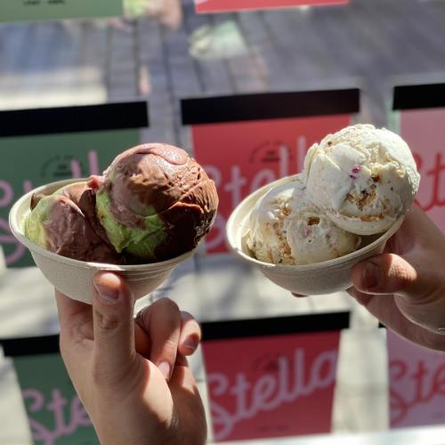 Two hands holding bowls of ice cream: one with chocolate and mint, the other with vanilla and caramel. Colorful background.