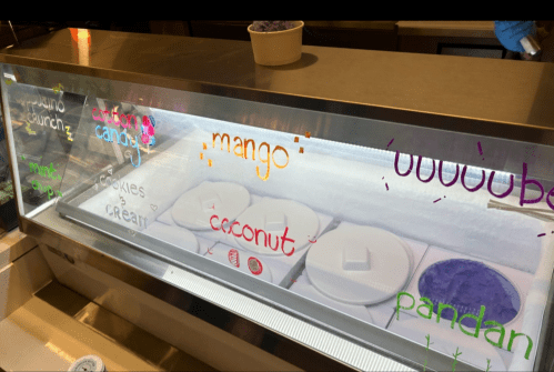 A display case with various ice cream flavors labeled: mango, coconut, pandan, cookies & cream, and cotton candy.