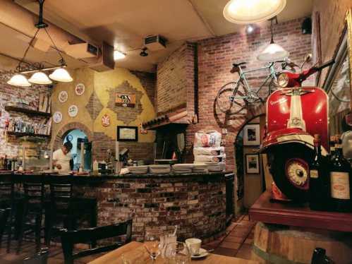 Cozy restaurant interior with brick walls, vintage decor, a bicycle, and a red scooter on display.
