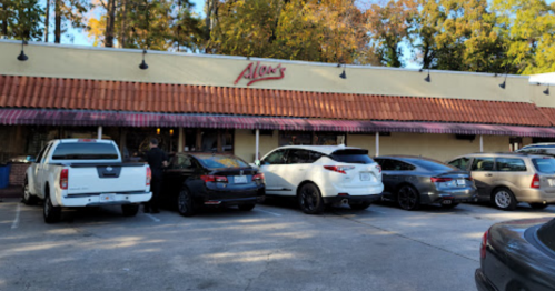 Exterior of Allan's restaurant with parked cars in front and trees in the background.