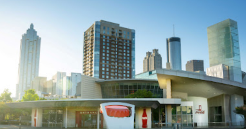 Skyline of Atlanta with modern buildings and the Coca-Cola Museum in the foreground, bathed in morning light.