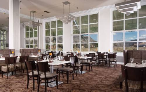 A modern restaurant interior with large windows, elegant tables, and stylish lighting fixtures.