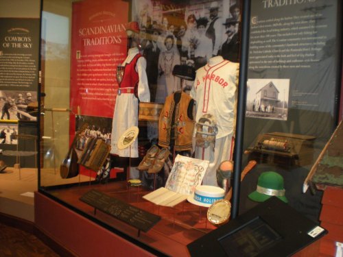 Display of historical artifacts showcasing Scandinavian traditions and local history, including clothing and sports memorabilia.