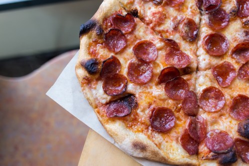 A close-up of a pepperoni pizza with a crispy crust, resting on a wooden table.