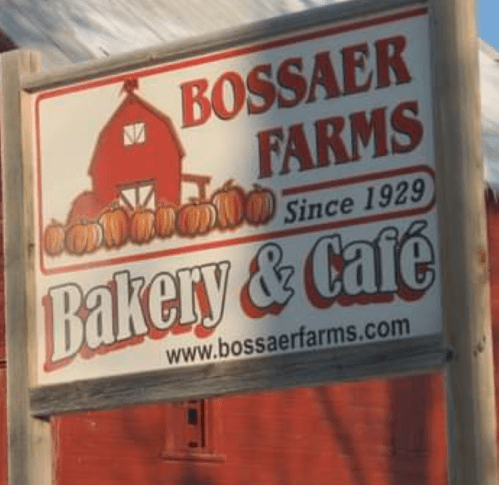 Sign for Bossaer Farms Bakery & Café, featuring pumpkins and a barn, established in 1929.