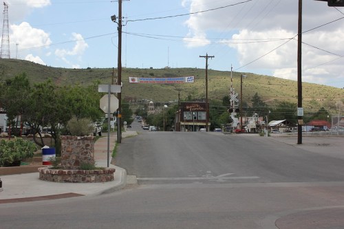 A quiet street scene with a view of a small town, mountains in the background, and a banner overhead.