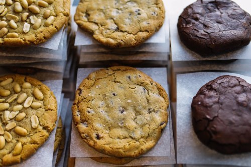 A variety of cookies, including chocolate chip and chocolate, arranged on parchment paper.