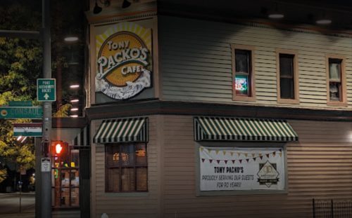 A corner view of Tony Packo's Cafe, featuring a colorful sign and striped awnings, illuminated at night.