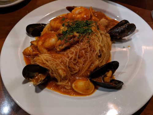 A plate of seafood pasta with shrimp, mussels, and a rich tomato sauce, garnished with parsley.
