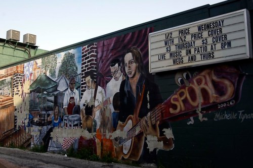 A colorful mural depicting musicians and a lively outdoor scene, with a sign advertising live music and drink specials.
