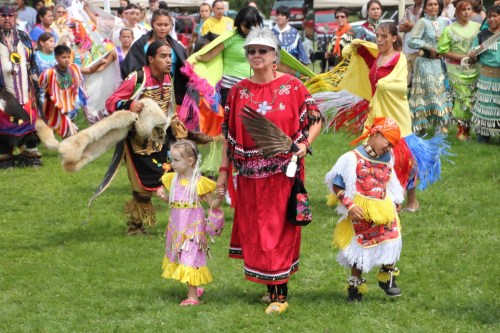 A group of people in traditional attire dance together outdoors, showcasing vibrant colors and cultural heritage.